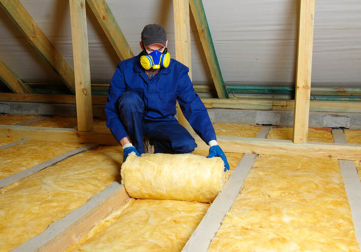 Construction worker thermally insulating house attic with glass wool in wilton