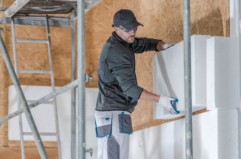 Person installing insulation into the wall of a commercial building in Wilton, CT.