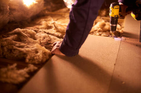 Person securing floor boards on top of insulation in a wilton.