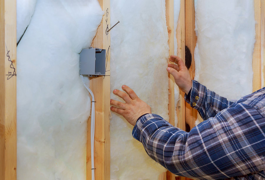 Person installing insulation into an attic panel in Wilton.